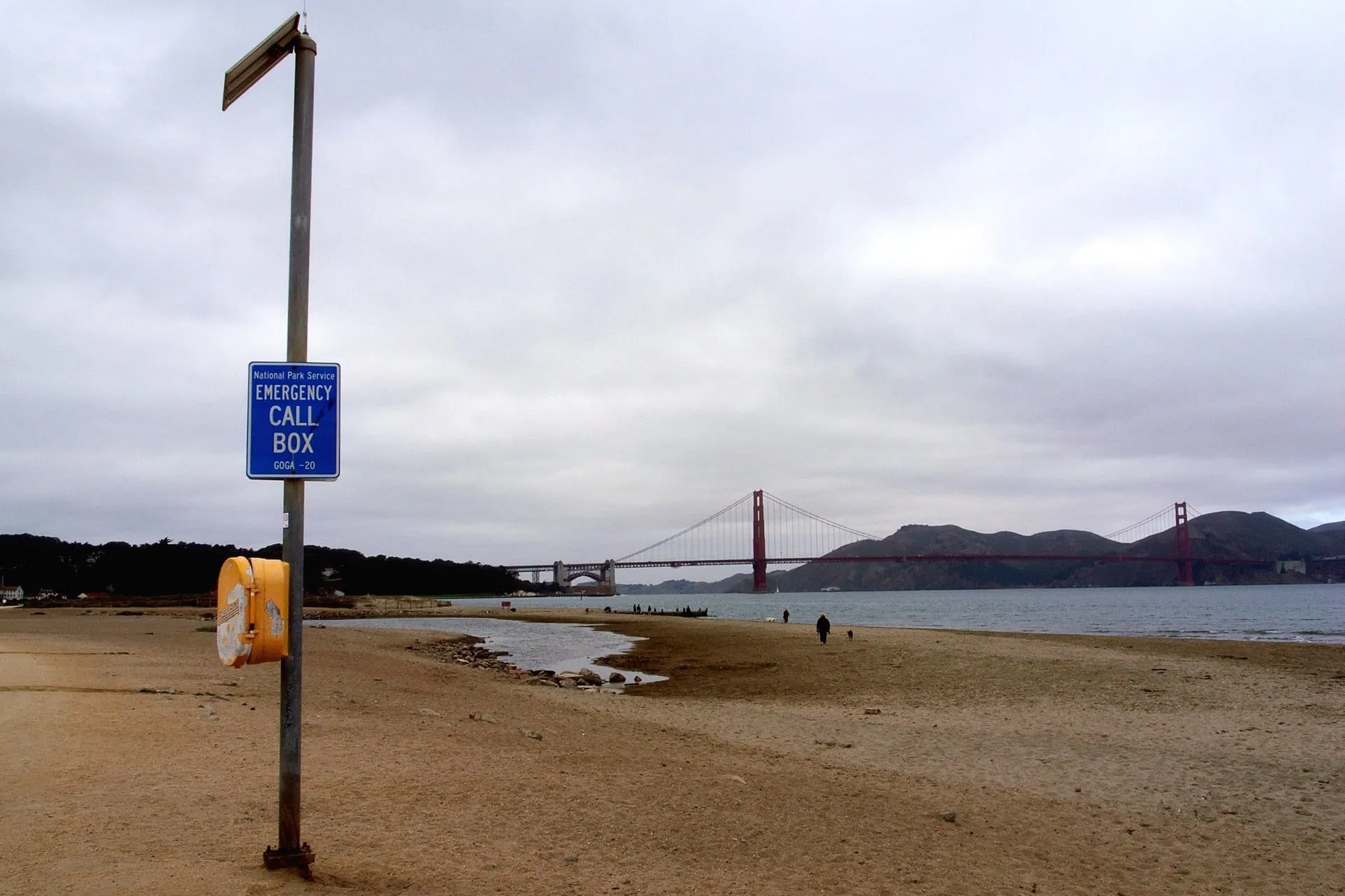 Eine Notrufsäule am Sandstrand mit Blick auf die Golden Gate Bridge.