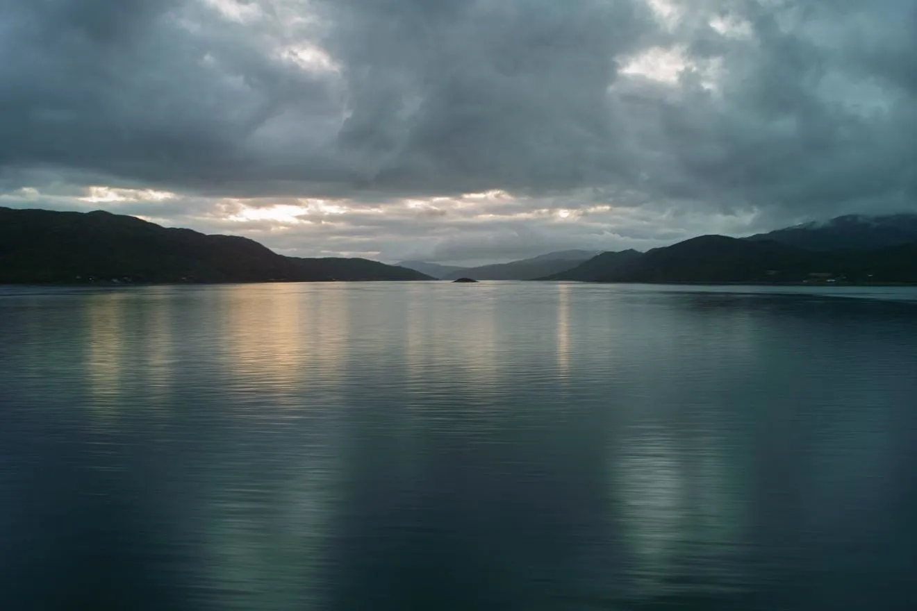 Stille Abendstimmung über dem Fjord, Wolken spiegeln sich im ruhigen Wasser.